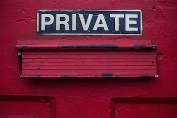 A red door with a letter slot in it, with the word "Private" written above the slot