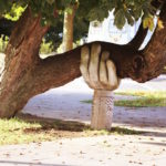 Sculpture of a large hand holding up a large tree limb