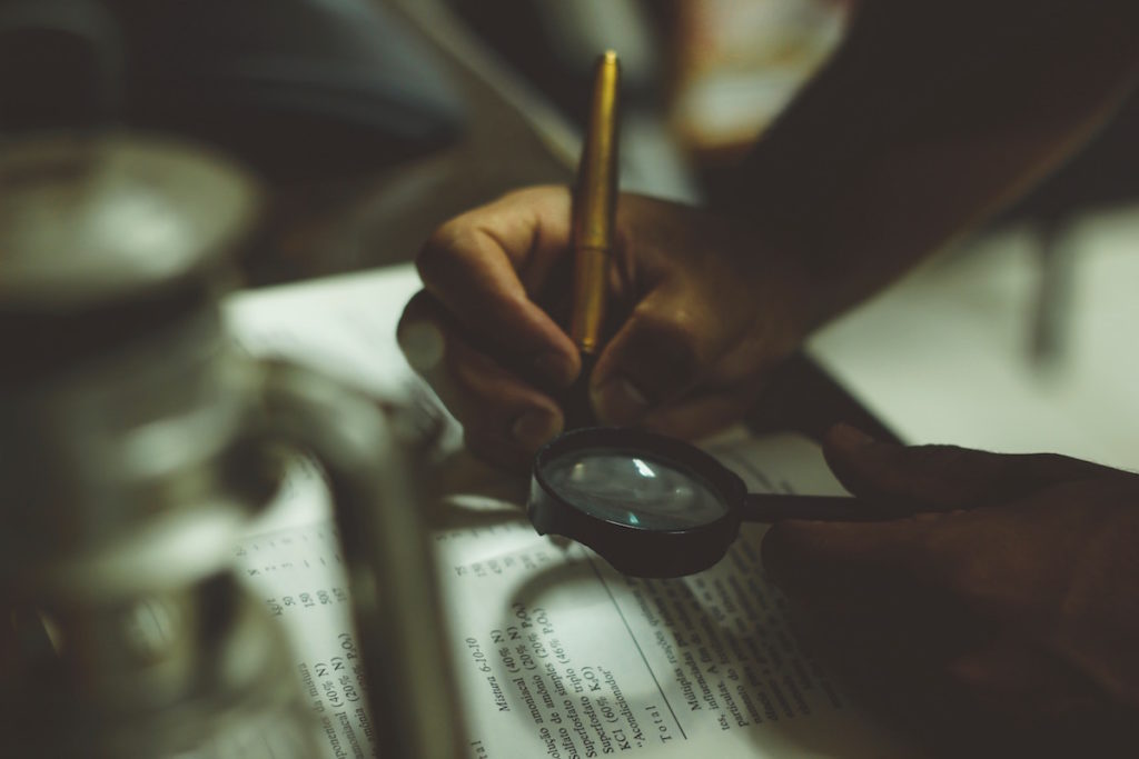 A person reading a book with a magnifying glass