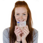 Young woman holding a drivers license in front of her