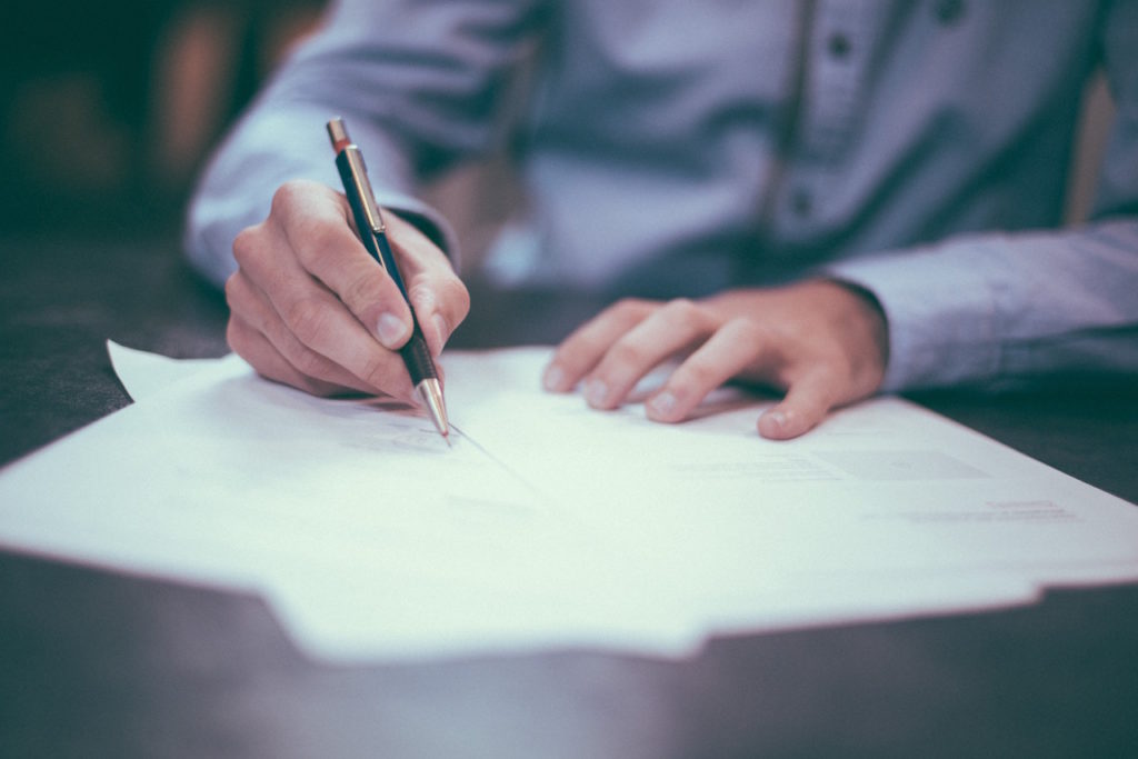 Man's hand writing on paper with fancy pen