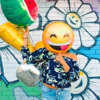 Woman holding a balloon in front of her face