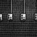 Black and white image of several old pay phones in a row on a wall