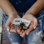 Someone's hands holding coins and a sheet of paper saying, "Make a change"