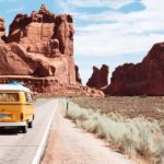 Vanagon driving down road towards desert rocks